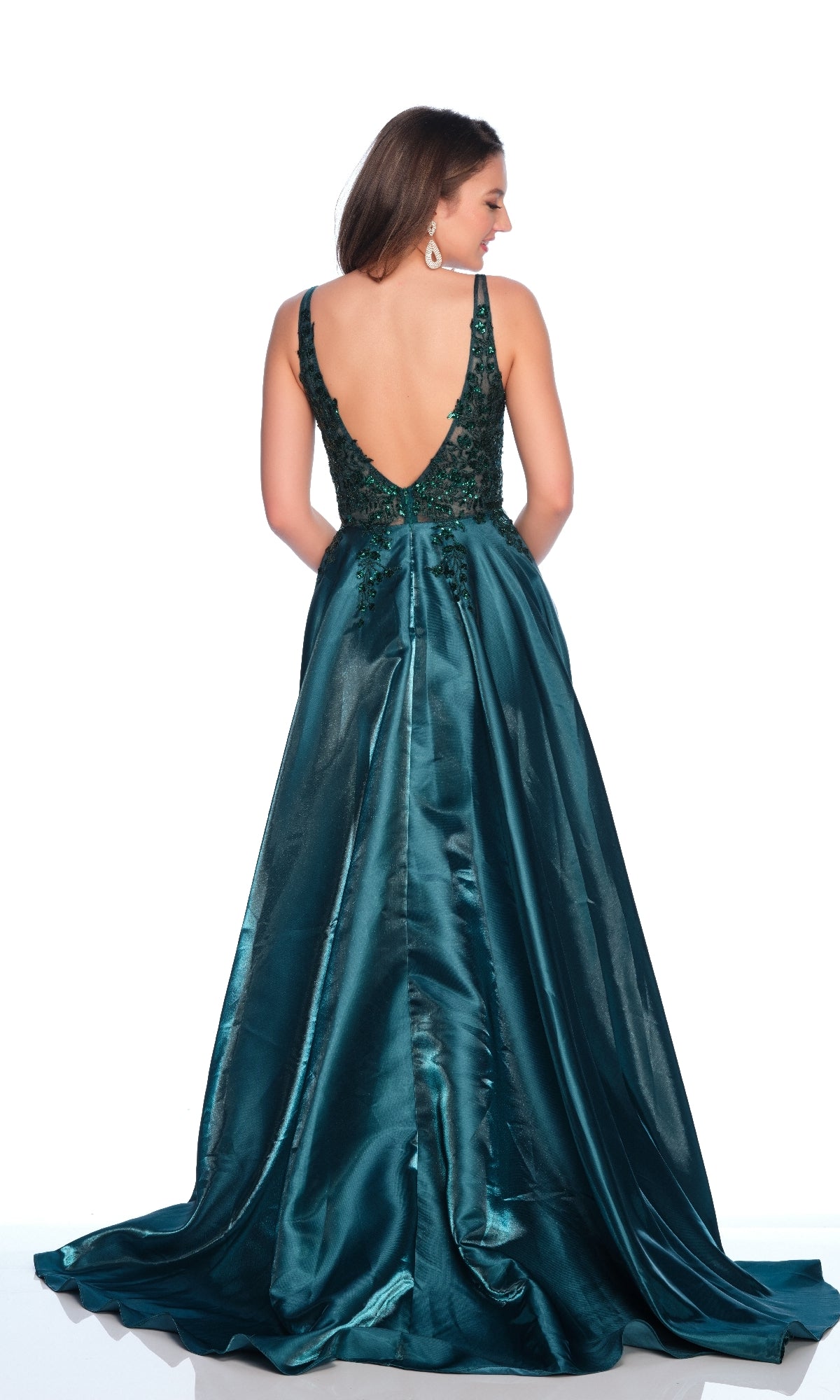 A woman poses against a white background wearing the Dave & Johnny 12104 Emerald Green Prom Dress, featuring a sleeveless design, deep V-back, sequin illusion bodice, and a shiny floor-length skirt.